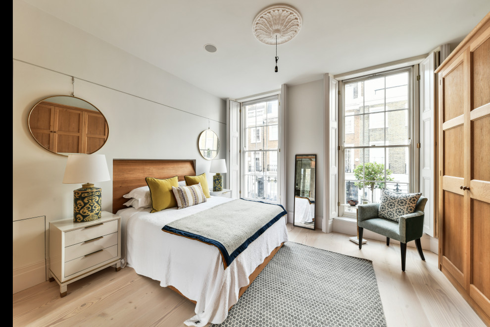 This is an example of a scandi bedroom in London with white walls, light hardwood flooring and beige floors.