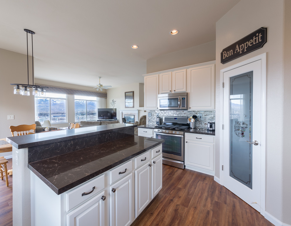 Eat-in kitchen - mid-sized transitional u-shaped eat-in kitchen idea with a single-bowl sink, raised-panel cabinets, white cabinets, quartzite countertops, gray backsplash, glass tile backsplash, stainless steel appliances and an island