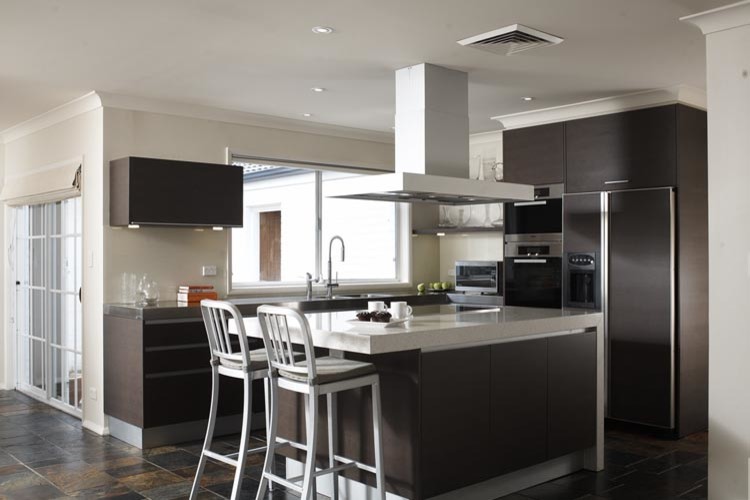 Photo of a mid-sized contemporary l-shaped eat-in kitchen in Sydney with an integrated sink, flat-panel cabinets, dark wood cabinets, solid surface benchtops, beige splashback, glass sheet splashback, stainless steel appliances, slate floors and with island.