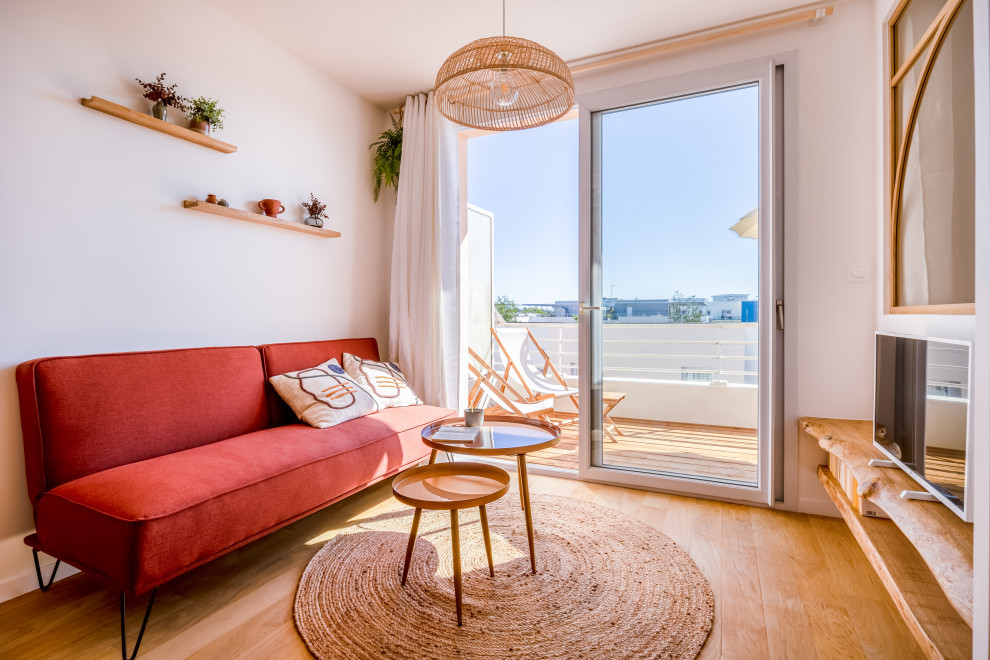 Diseño de salón abierto y blanco y madera escandinavo pequeño con paredes blancas, suelo de madera clara y televisor independiente