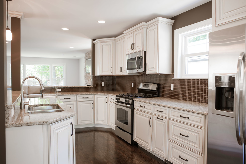 Mid-sized transitional galley dark wood floor kitchen photo in St Louis with raised-panel cabinets, white cabinets, granite countertops, brown backsplash, mosaic tile backsplash, stainless steel appliances and an island