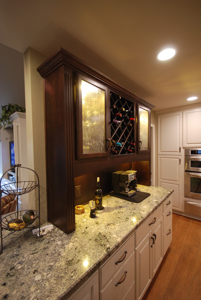 Large traditional u-shaped kitchen in Other with a double-bowl sink, raised-panel cabinets, dark wood cabinets, granite worktops, beige splashback, stone tiled splashback, stainless steel appliances, porcelain flooring and an island.