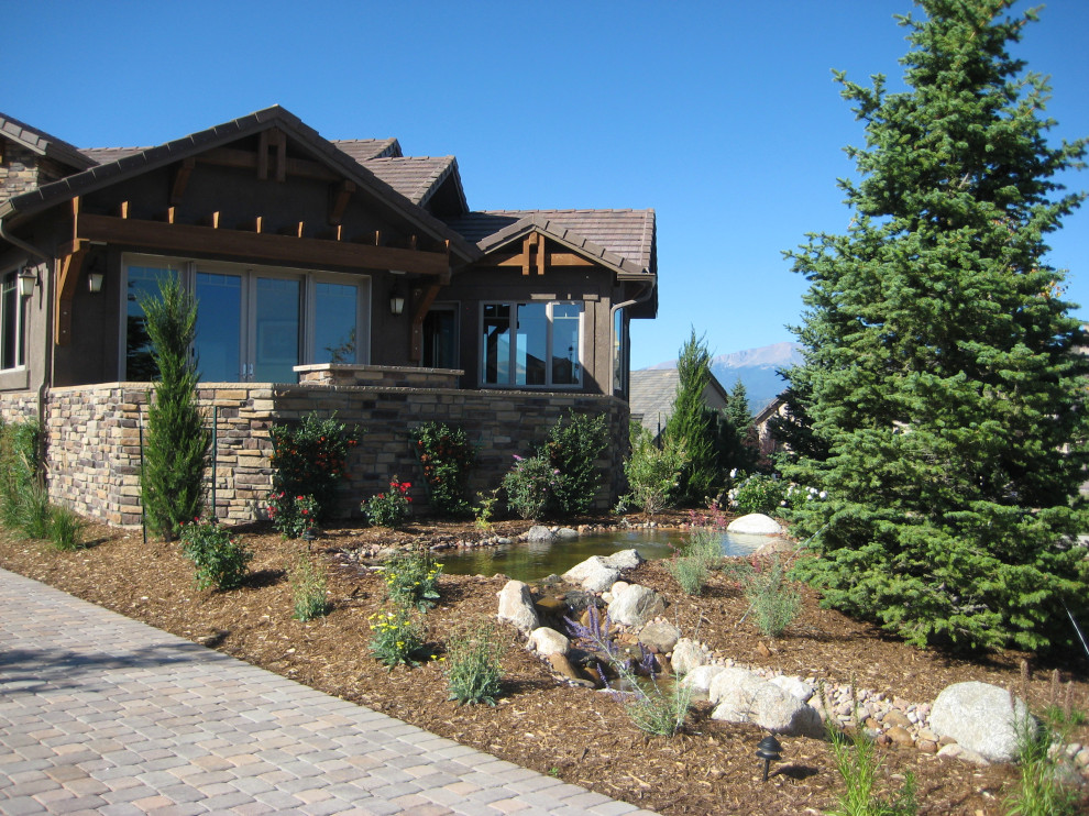 This is an example of a large traditional front yard full sun driveway for spring in Denver with with waterfall and brick pavers.