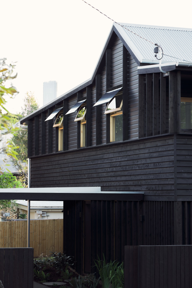 Immagine della villa nera moderna a due piani di medie dimensioni con rivestimento in legno, tetto a capanna, copertura in metallo o lamiera e pannelli sovrapposti