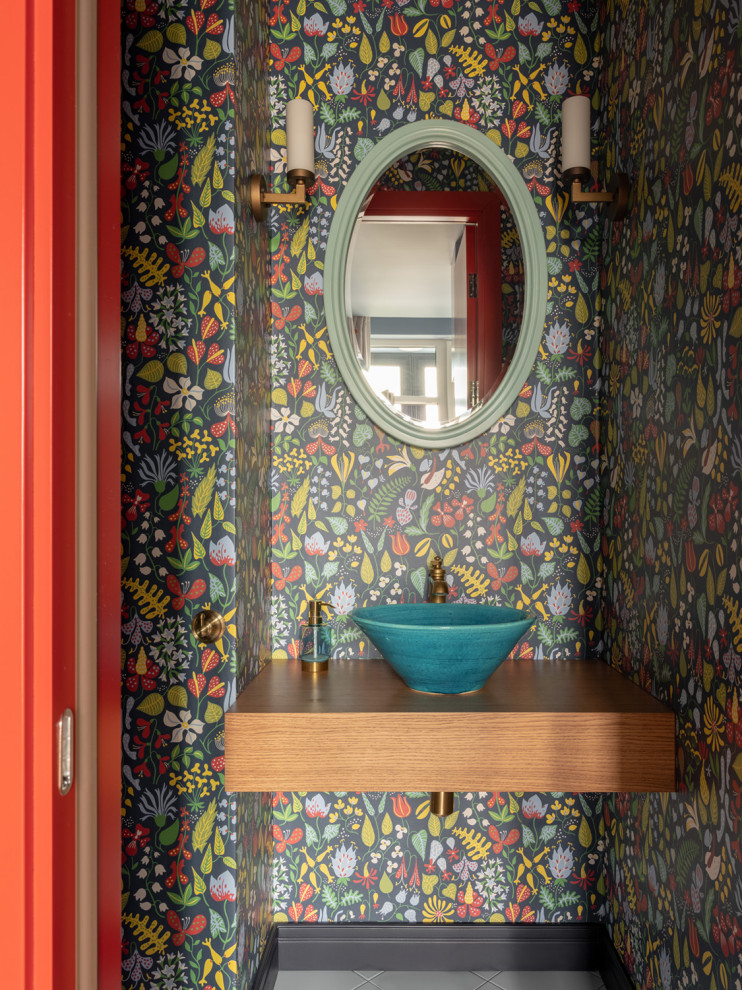This is an example of a contemporary powder room in Moscow with multi-coloured walls, a vessel sink and brown benchtops.