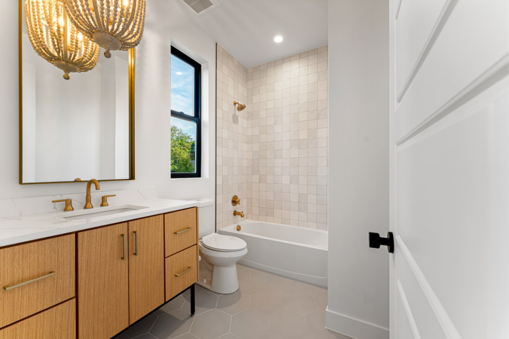 Modern kids bathroom in Denver with flat-panel cabinets, light wood cabinets, a drop-in tub, a shower/bathtub combo, white tile, porcelain tile, white walls, porcelain floors, an undermount sink, quartzite benchtops, grey floor, a shower curtain, white benchtops, a single vanity and a freestanding vanity.
