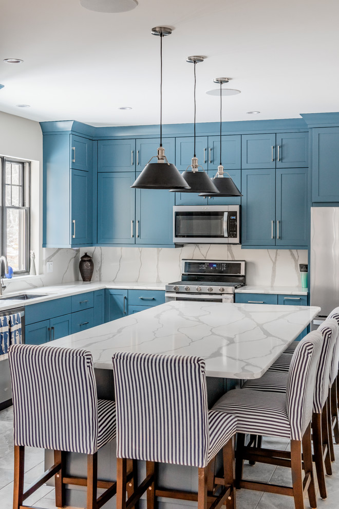 Design ideas for a transitional l-shaped kitchen in Boston with an undermount sink, shaker cabinets, blue cabinets, white splashback, stone slab splashback, stainless steel appliances, with island and white benchtop.