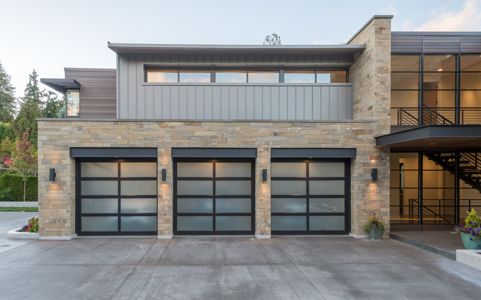 This is an example of a large contemporary attached three-car garage in Seattle.