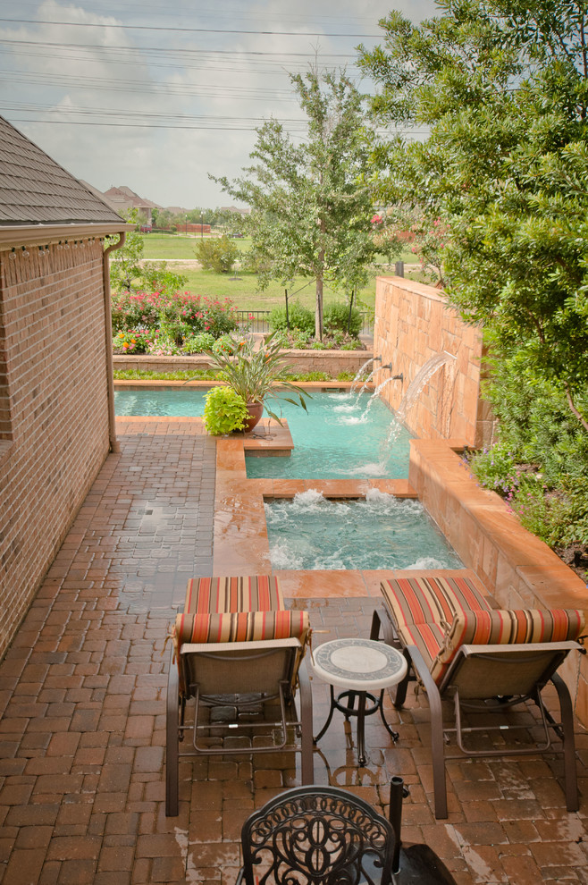 Design ideas for a mid-sized traditional side yard l-shaped pool in Houston with a hot tub and natural stone pavers.