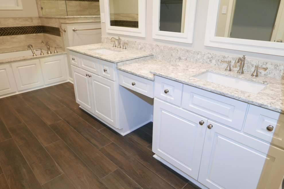 This is an example of a large traditional master bathroom in Other with raised-panel cabinets, white cabinets, an undermount tub, a corner shower, a bidet, gray tile, porcelain tile, grey walls, porcelain floors, an undermount sink, engineered quartz benchtops, brown floor, a hinged shower door and multi-coloured benchtops.