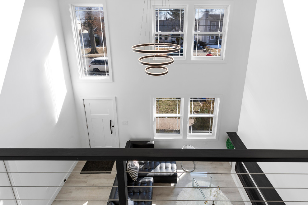 Modern Residential Construction - Inspiration for a large modern formal and loft-style light wood floor, brown floor, vaulted ceiling and wall paneling living room remodel in Newark with white walls, a standard fireplace, a wood fireplace surround and a wall-mounted tv