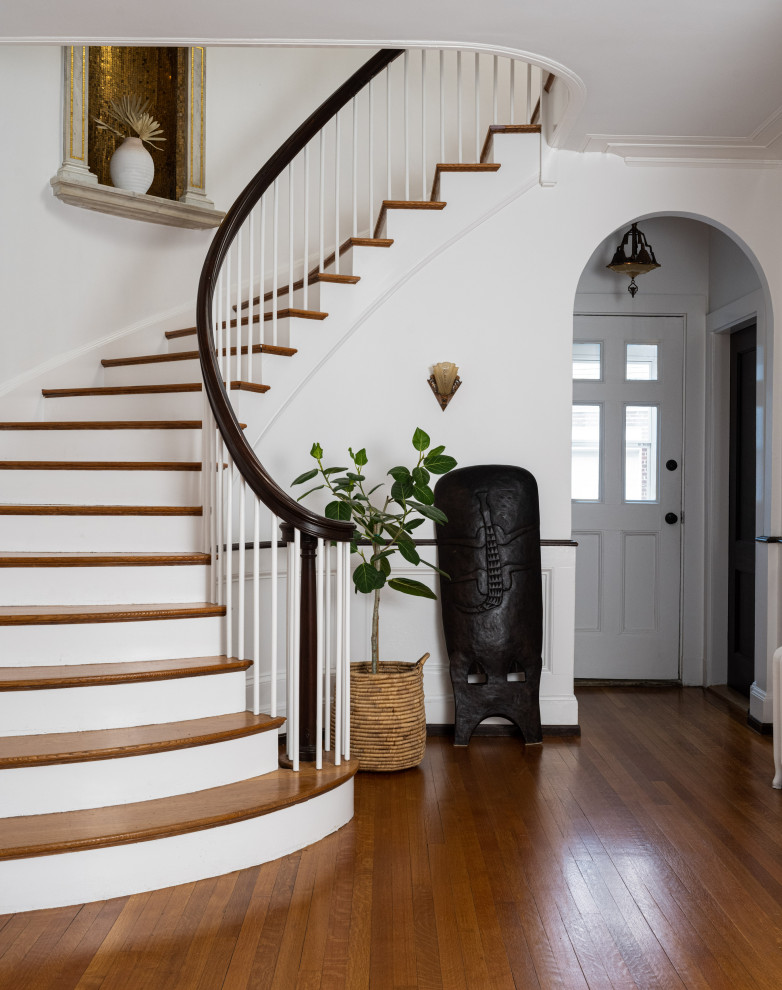 Cette image montre un escalier peint courbe traditionnel avec des marches en bois et un garde-corps en bois.