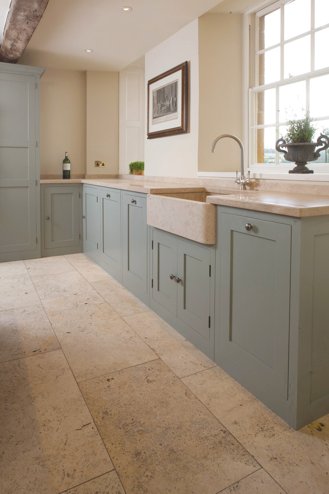 This is an example of a mid-sized country galley separate kitchen in London with a farmhouse sink, shaker cabinets, granite benchtops, beige splashback, stone tile splashback and with island.
