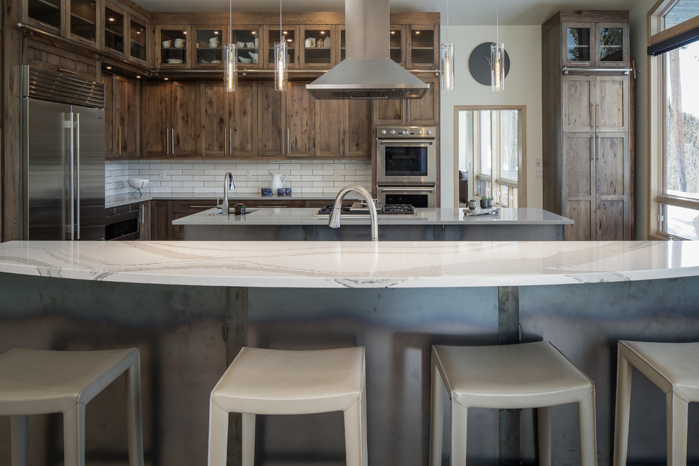 Inspiration for a huge transitional l-shaped light wood floor and brown floor open concept kitchen remodel in Denver with an undermount sink, shaker cabinets, medium tone wood cabinets, quartz countertops, white backsplash, subway tile backsplash, stainless steel appliances, two islands and multicolored countertops