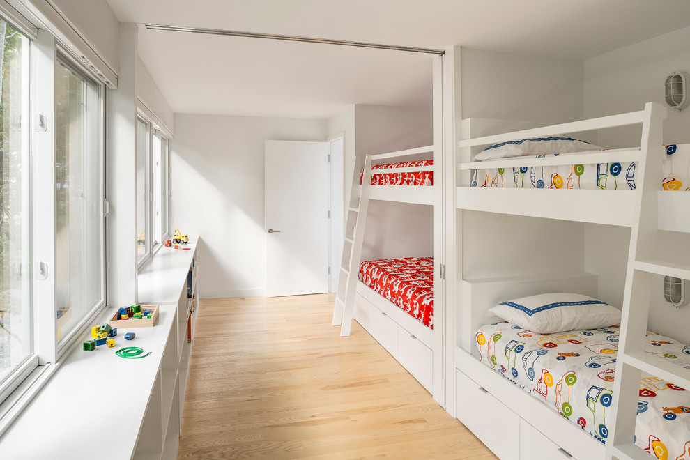 This is an example of a contemporary gender-neutral kids' bedroom for kids 4-10 years old in Portland Maine with white walls and light hardwood floors.
