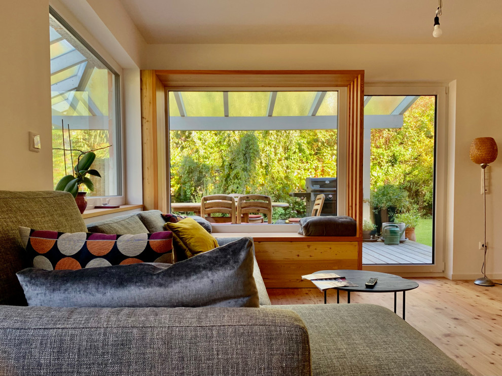 Imagen de salón de estilo de casa de campo grande con paredes blancas, suelo de madera clara y televisor independiente