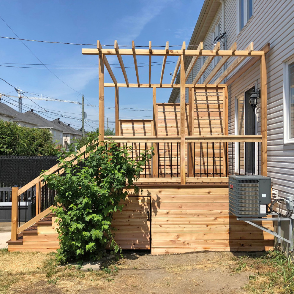 Photo of a mid-sized arts and crafts backyard deck in Montreal with with privacy feature and a pergola.