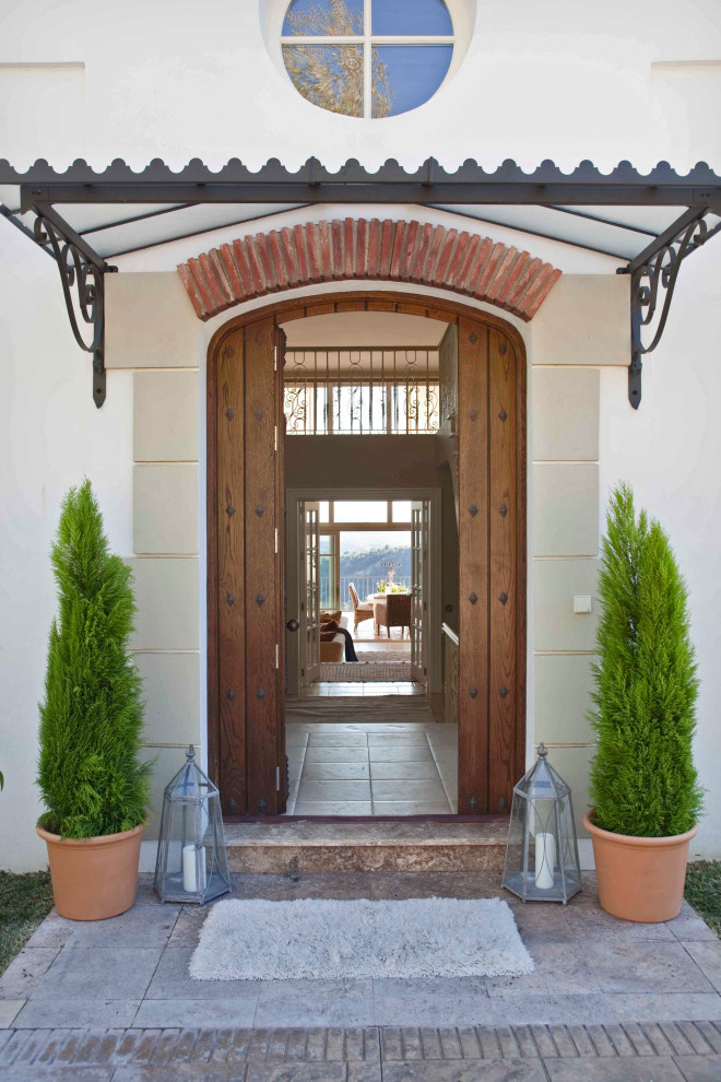 Imagen de puerta principal campestre grande con paredes blancas, suelo de baldosas de cerámica, puerta doble, puerta de madera en tonos medios y suelo beige
