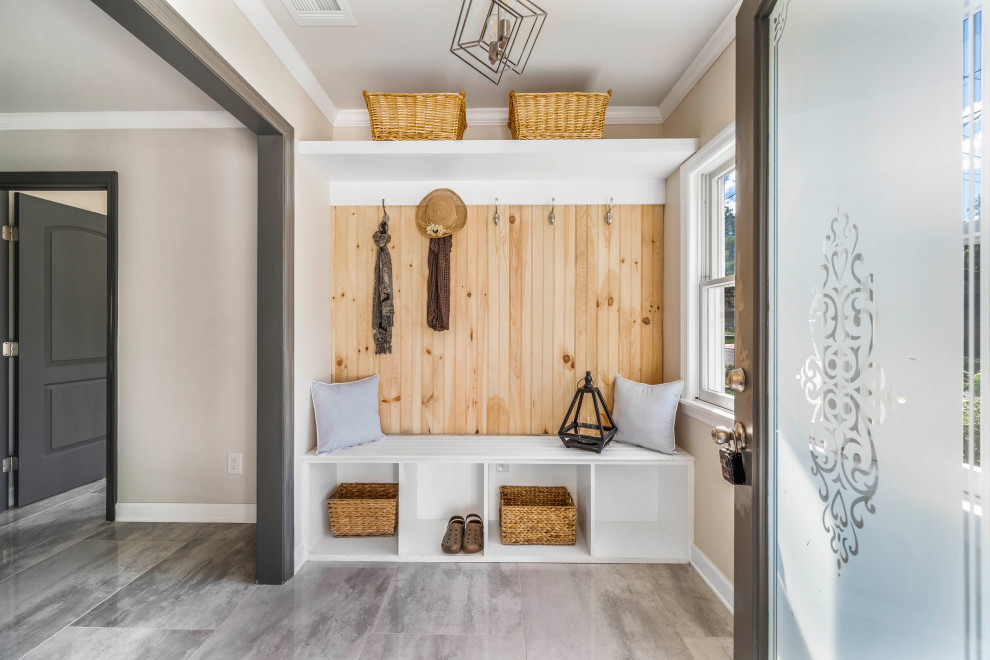 Example of a transitional gray floor mudroom design in New York with beige walls and a glass front door