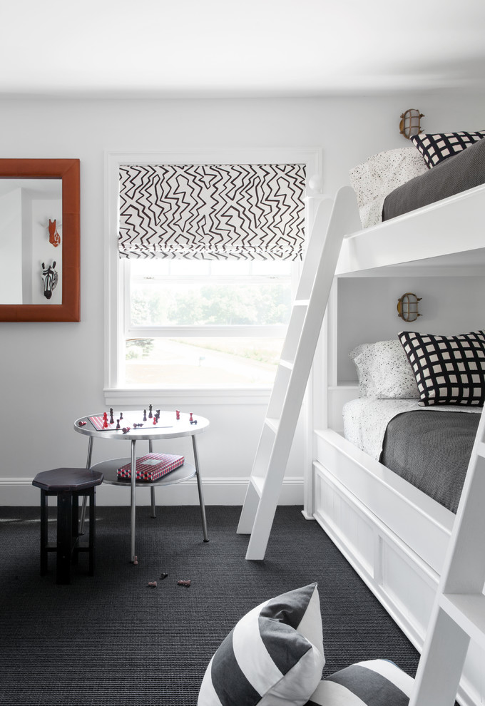 Photo of a beach style gender-neutral kids' bedroom in New York with white walls, carpet and grey floor.