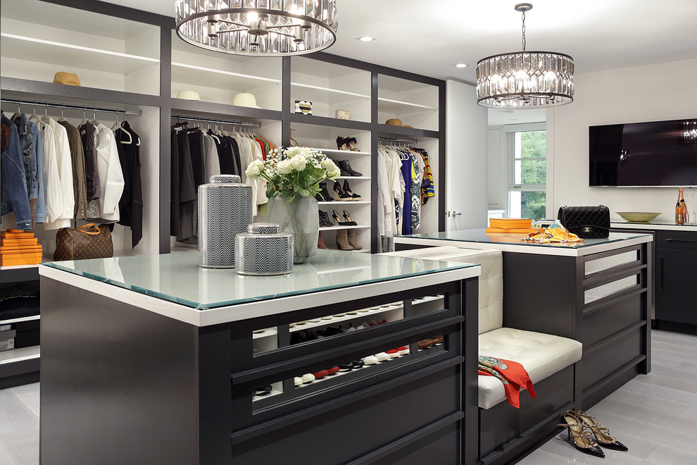 This is an example of a contemporary gender-neutral dressing room in New York with open cabinets and grey floor.