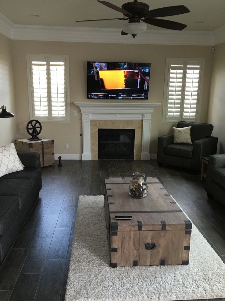 Inspiration for a mid-sized transitional open concept living room in Phoenix with beige walls, dark hardwood floors, a wood stove, a wood fireplace surround and a wall-mounted tv.