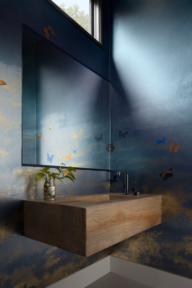 Minimalist gray floor and wallpaper powder room photo in New York with brown cabinets, multicolored walls, an integrated sink, wood countertops, brown countertops and a floating vanity