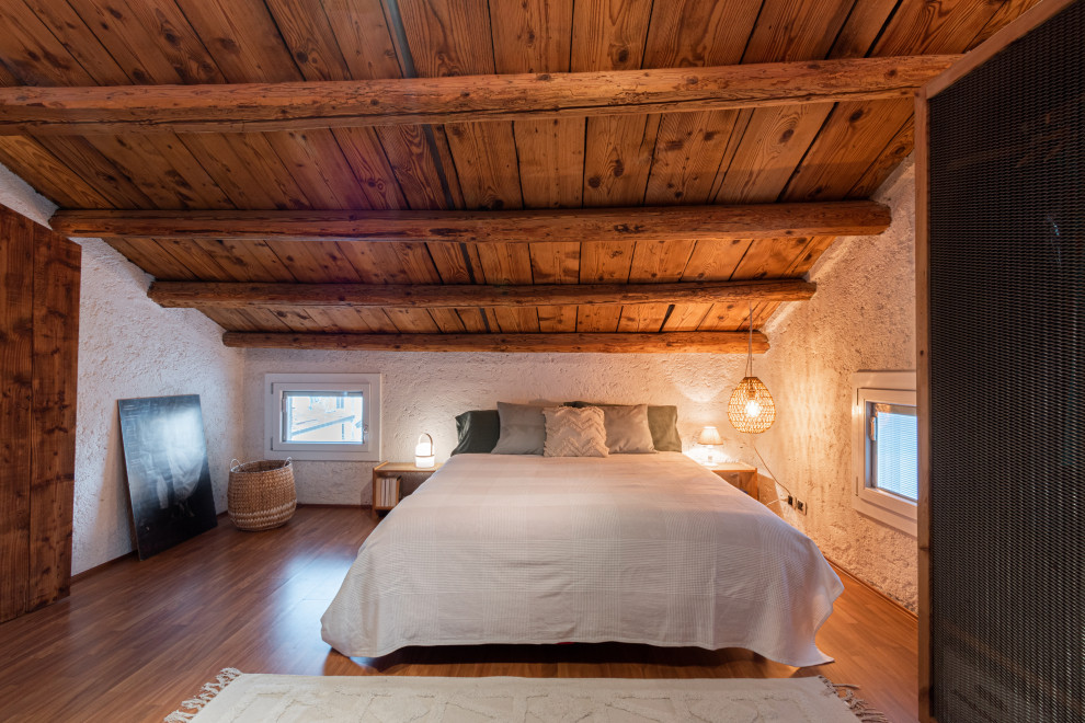 This is an example of a mid-sized country master bedroom in Venice with white walls, linoleum floors, orange floor and exposed beam.