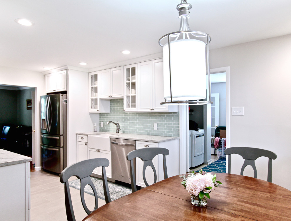 Photo of a large transitional galley eat-in kitchen in Philadelphia with a farmhouse sink, shaker cabinets, white cabinets, quartz benchtops, green splashback, glass tile splashback, stainless steel appliances, porcelain floors, no island, grey floor and multi-coloured benchtop.