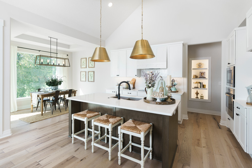 Open concept kitchen - mid-sized scandinavian l-shaped light wood floor, brown floor and vaulted ceiling open concept kitchen idea in Wichita with a double-bowl sink, quartzite countertops, white backsplash, ceramic backsplash, stainless steel appliances, an island, white countertops, flat-panel cabinets and brown cabinets