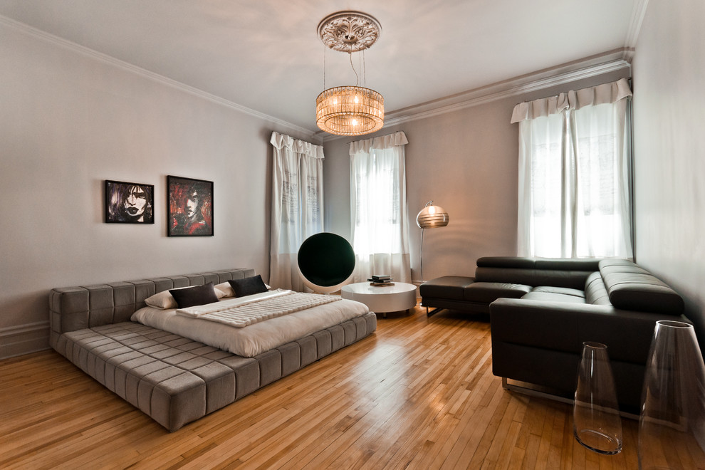 This is an example of a large contemporary guest bedroom in Montreal with white walls and light hardwood floors.