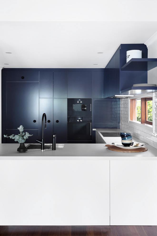 Inspiration for a mid-sized contemporary u-shaped eat-in kitchen in Melbourne with an undermount sink, flat-panel cabinets, blue cabinets, quartz benchtops, white splashback, window splashback, black appliances and dark hardwood floors.