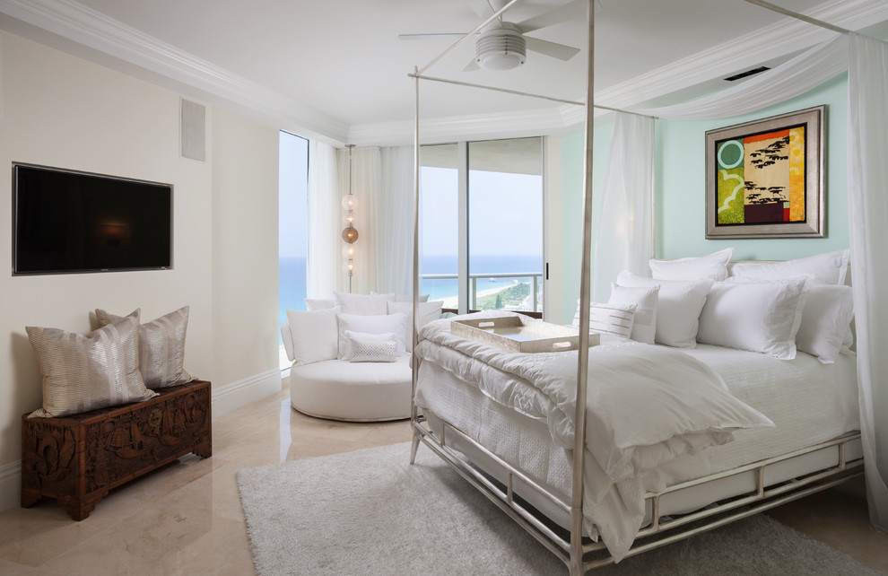 Photo of a large beach style bedroom in Miami with blue walls, marble floors and beige floor.