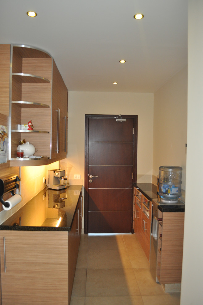 Example of a mid-sized minimalist galley ceramic tile and beige floor enclosed kitchen design with a double-bowl sink, flat-panel cabinets, medium tone wood cabinets, granite countertops, beige backsplash, ceramic backsplash, stainless steel appliances, an island and black countertops
