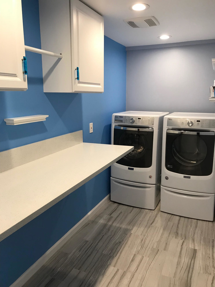 Photo of a small transitional l-shaped laundry room in Los Angeles with raised-panel cabinets, white cabinets, blue walls, porcelain floors, a side-by-side washer and dryer and multi-coloured floor.