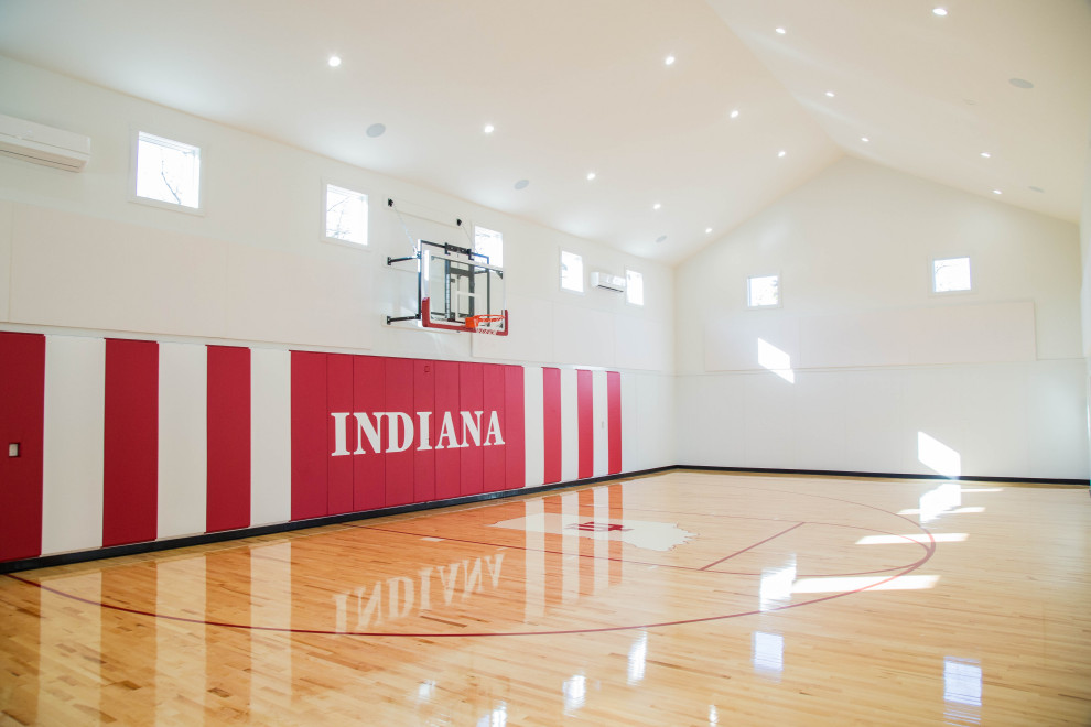 Geräumiger Klassischer Fitnessraum mit Indoor-Sportplatz, weißer Wandfarbe, gebeiztem Holzboden, buntem Boden und gewölbter Decke in Indianapolis