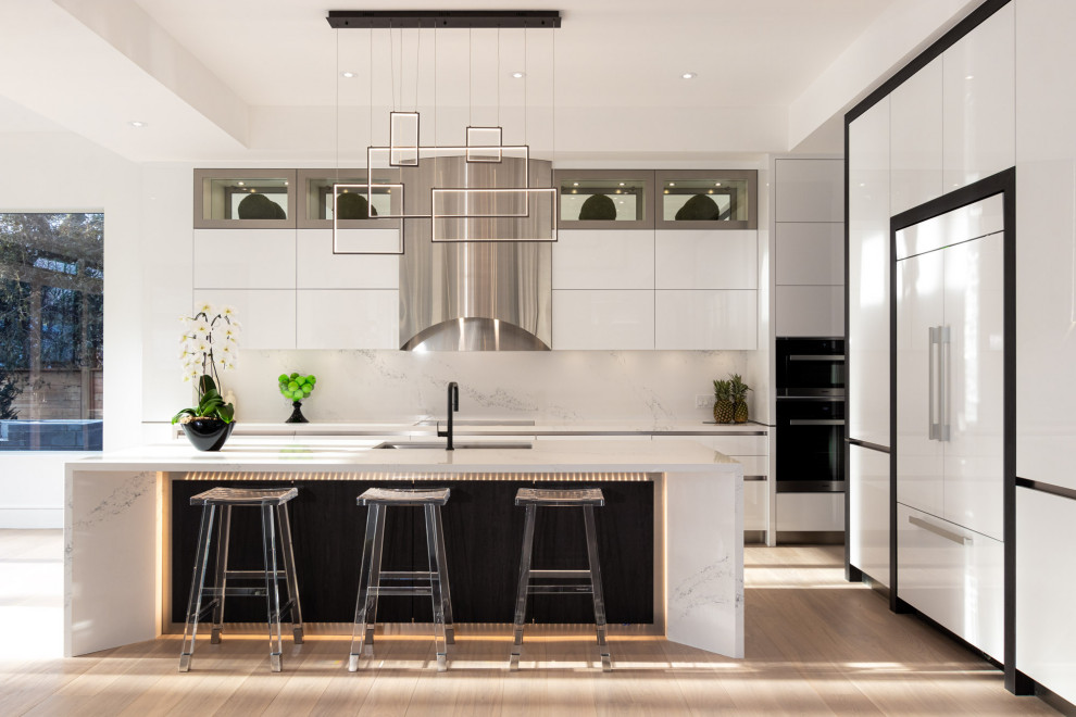 Inspiration for a contemporary l-shaped kitchen in Toronto with an undermount sink, flat-panel cabinets, white cabinets, white splashback, white appliances, light hardwood floors, with island, beige floor, white benchtop and recessed.