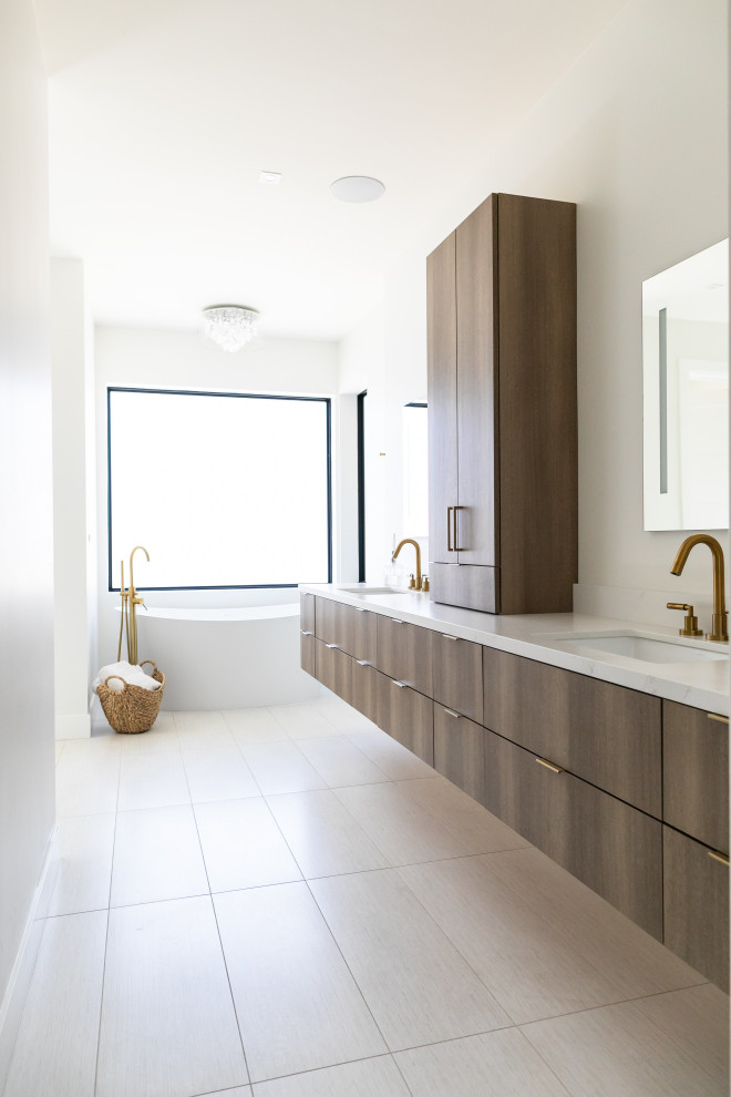 This is an example of a large contemporary ensuite bathroom in San Francisco with flat-panel cabinets, medium wood cabinets, a freestanding bath, white walls, porcelain flooring, a submerged sink, engineered stone worktops, white floors, white worktops, double sinks and a floating vanity unit.