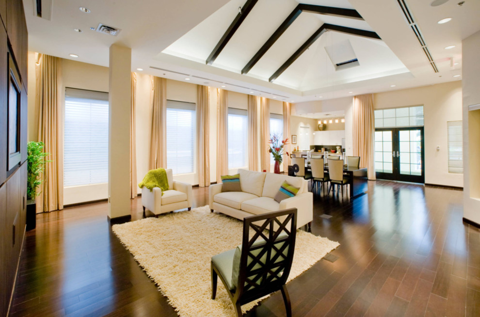 Example of a large minimalist enclosed dark wood floor and brown floor living room design in San Diego with a bar, beige walls, no fireplace and a media wall