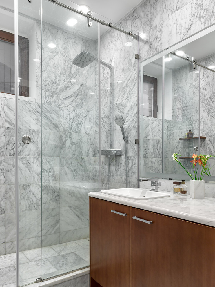 This is an example of a contemporary 3/4 bathroom in Moscow with flat-panel cabinets, medium wood cabinets, an alcove shower, gray tile, stone tile, marble floors, a drop-in sink, marble benchtops and a sliding shower screen.