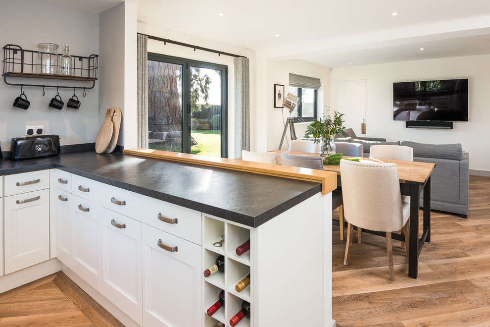 Photo of a mid-sized contemporary u-shaped open plan kitchen in Oxfordshire with shaker cabinets, white cabinets, laminate benchtops, vinyl floors, no island and brown floor.