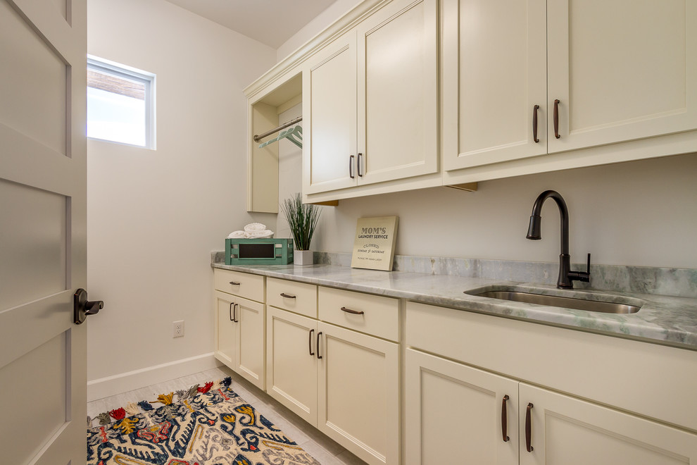 Design ideas for a mid-sized transitional single-wall dedicated laundry room in Tampa with an undermount sink, recessed-panel cabinets, white cabinets, onyx benchtops, white walls and porcelain floors.