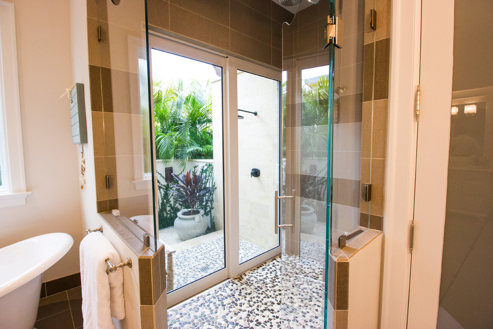 Mid-sized mediterranean master bathroom in Tampa with a freestanding tub, a corner shower, beige tile, brown tile, ceramic tile, beige walls, ceramic floors, brown floor and a hinged shower door.