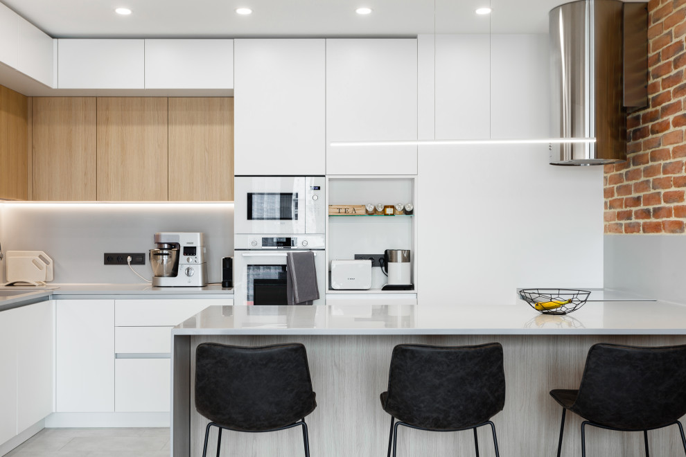 Design ideas for a mid-sized contemporary l-shaped open plan kitchen in Moscow with an undermount sink, flat-panel cabinets, white cabinets, solid surface benchtops, grey splashback, white appliances, porcelain floors, a peninsula, grey floor, grey benchtop and recessed.