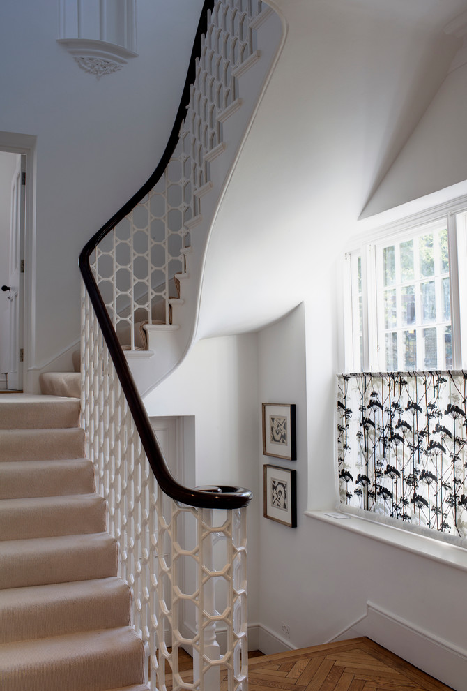 This is an example of a mid-sized eclectic carpeted curved staircase in London with carpet risers.