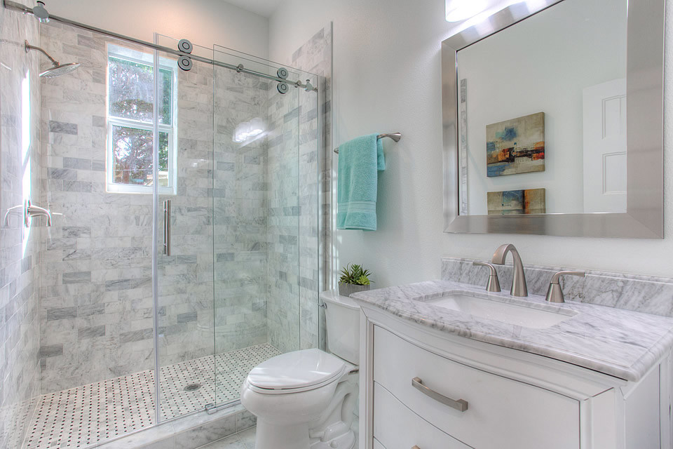 This is an example of a small contemporary 3/4 bathroom in Tampa with white cabinets, a two-piece toilet, white tile, gray tile, white walls, ceramic floors, an undermount sink, marble benchtops, grey floor, a sliding shower screen, flat-panel cabinets, an alcove shower and marble.