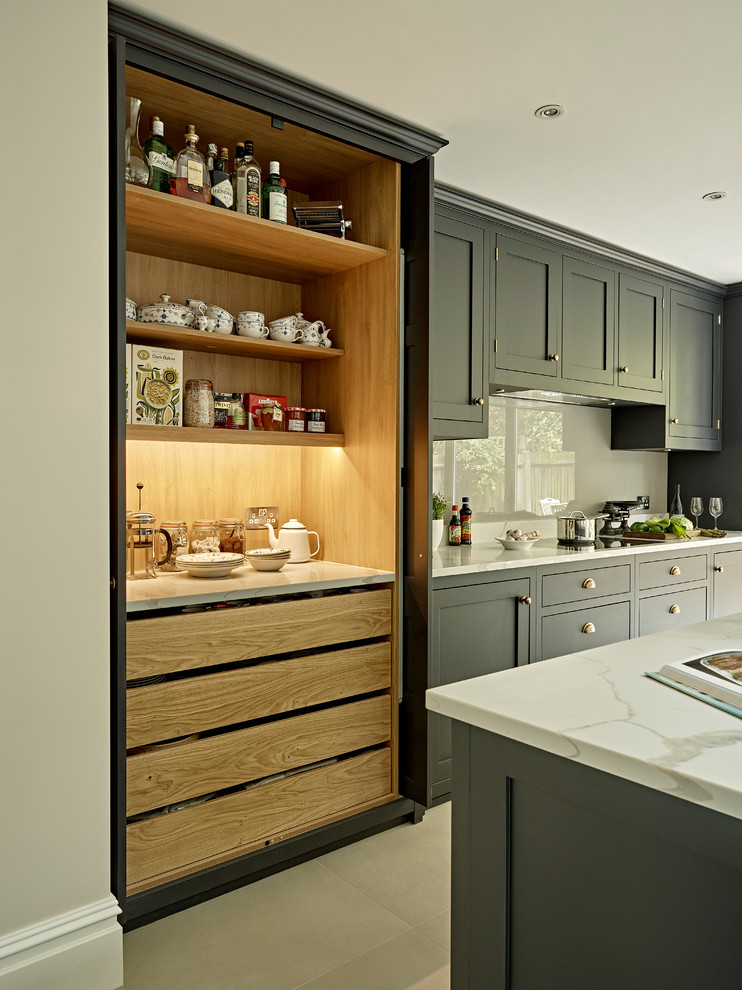 Photo of a large transitional eat-in kitchen in London with shaker cabinets, black cabinets, solid surface benchtops, grey splashback, porcelain floors, with island and grey floor.