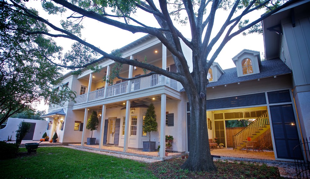 Photo of an expansive traditional two-storey stucco beige house exterior in Houston with a shingle roof, a grey roof and board and batten siding.