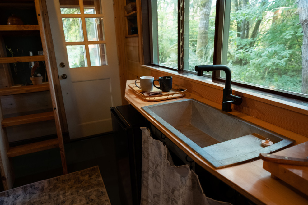 Foto på ett litet rustikt flerfärgad kök, med en nedsänkt diskho, skåp i shakerstil, skåp i mellenmörkt trä, träbänkskiva, stänkskydd i trä, svarta vitvaror, målat trägolv och grönt golv