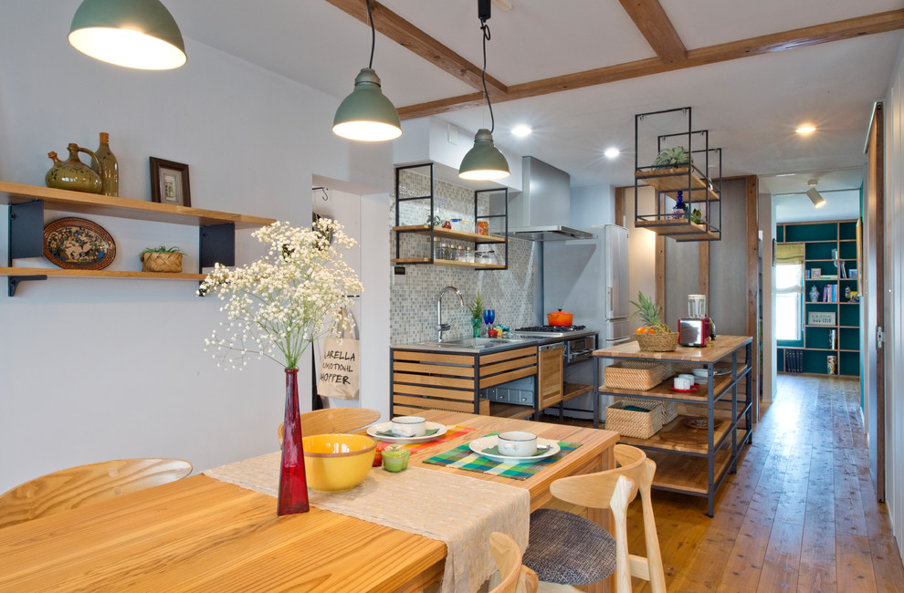 This is an example of an asian galley open plan kitchen in Yokohama with a single-bowl sink, open cabinets, stainless steel benchtops, multi-coloured splashback, medium hardwood floors, with island and brown floor.